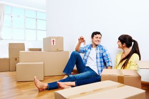 couple celebrating new home handing keys and moving boxes
