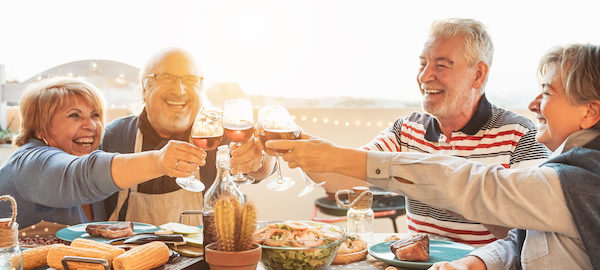 Happy senior dining and tasting red wine glasses in barbecue dinner party - Family having fun enjoying bbq at sunset time on terrace - Elderly people lifestyle and food and drink concept