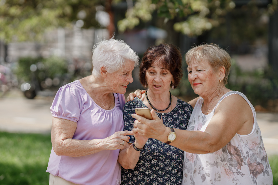 Three senior women looking at phone