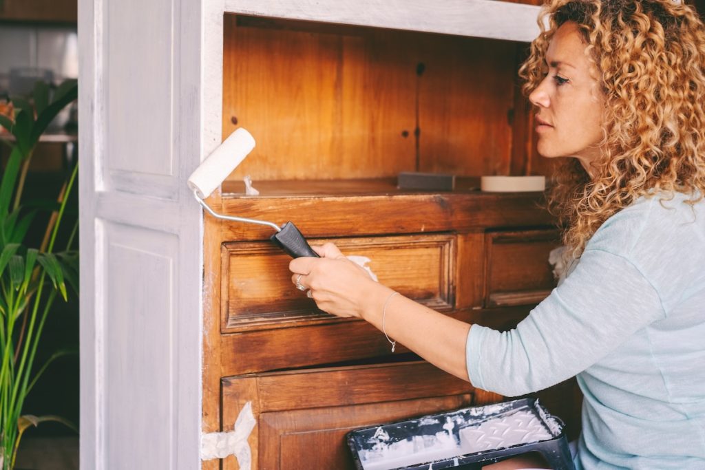 Woman painting an old antique cabinet 